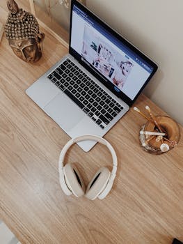 Stylish workspace in São Paulo featuring a laptop, headphones, and Buddha head sculpture.